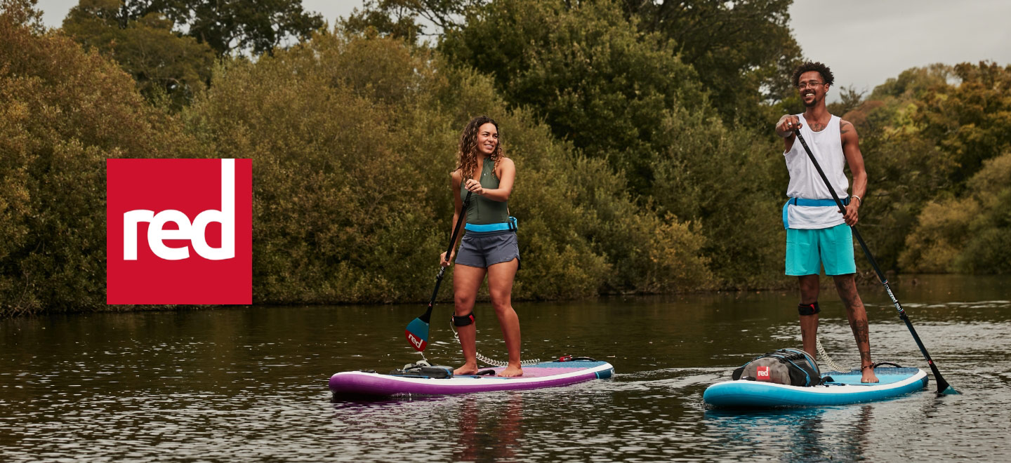 two people using red paddleboards on river
